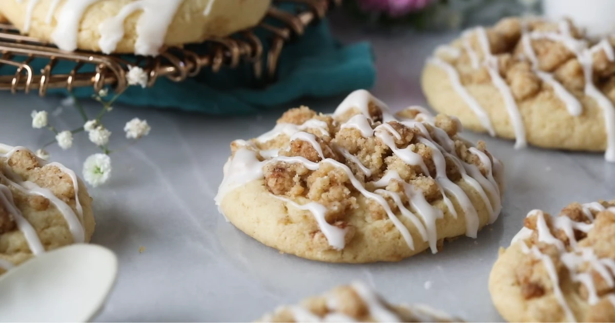 A batch of freshly baked coffee cookies with a golden-brown texture, placed on a wooden surface with coffee beans scattered around.