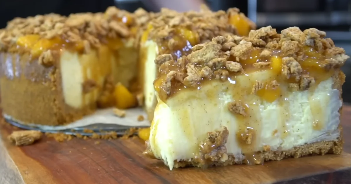 A slice of creamy Peach Cobbler Cheesecake topped with fresh peach slices and a golden cobbler crust.