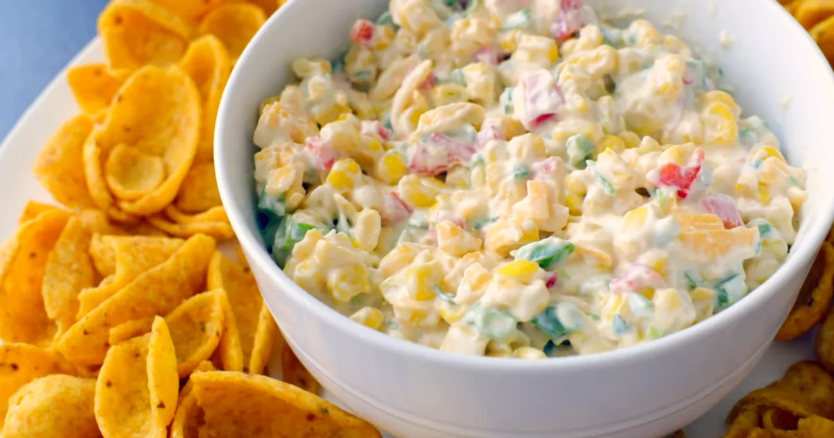 Creamy corn dip with cream cheese served with tortilla chips and fresh vegetables.