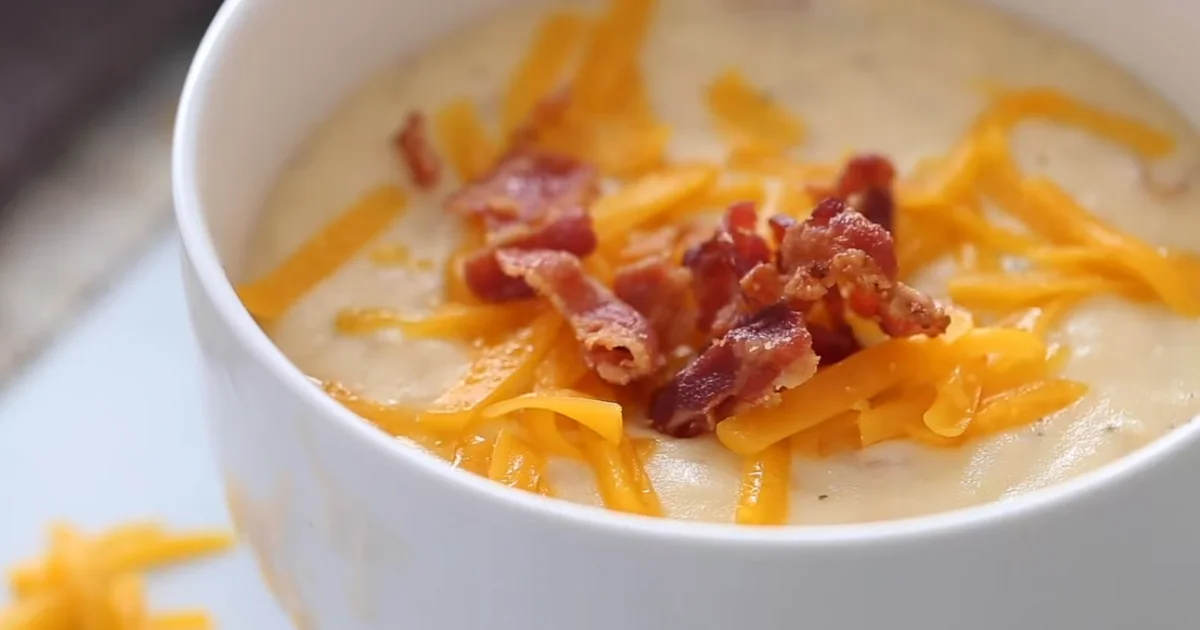A bowl of creamy Crock Pot Crack Potato Soup garnished with crispy bacon, shredded cheese, and green onions.
