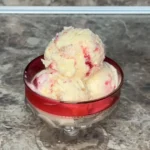 Creamy Strawberry Cheesecake Ice Cream with a graham cracker crust and fresh strawberries.